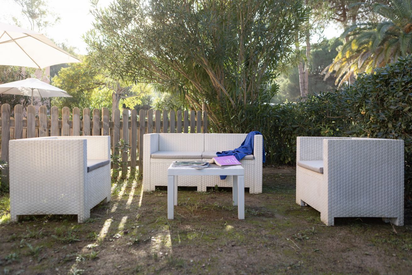 An outdoor seating area with wicker furniture, a white table, and a wooden fence.