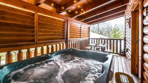 A wooden deck with a hot tub, wooden railings, and a table and chairs. - Bearadise City🐻 Loft Cabin w/ Mtn Views, Hot Tub, & Pool Table! (Pigeon Forge)