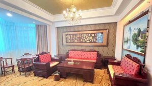 Ein Hotelzimmer mit großem Gemälde, einer Kandelaber, einer Sofagarnitur, einem Esstisch und Stühlen.