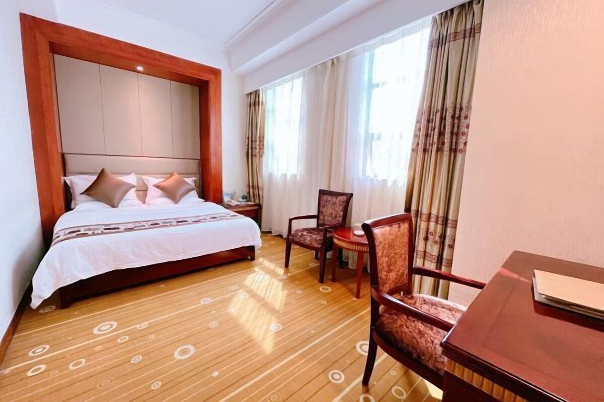 A hotel room with a bed, two chairs, a small table, and a nightstand.