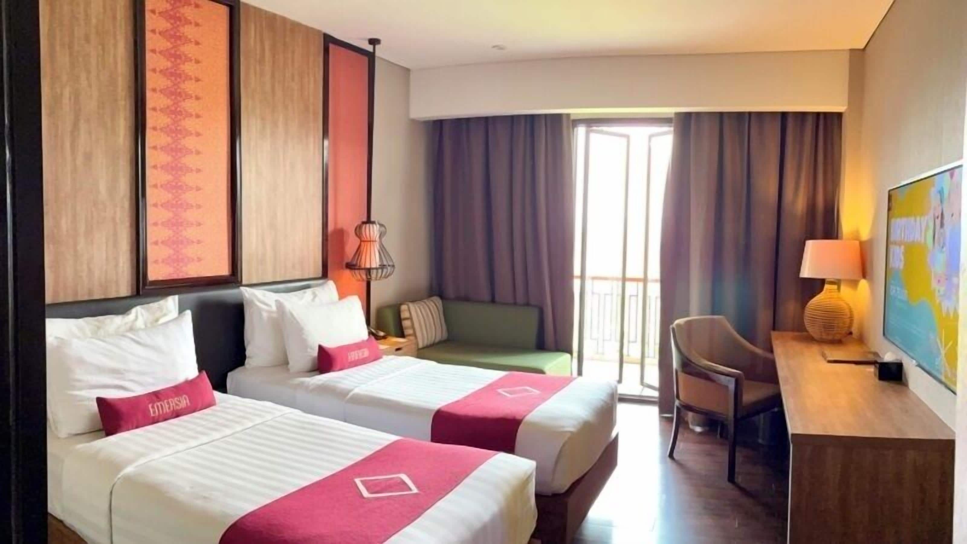 A hotel room with two beds, a desk, a chair, a lamp, and a television.