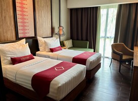 Habitación de hotel con dos camas, un sofá verde, una silla y vistas al exterior.
