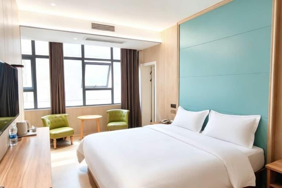 Hotellihuone, jossa on sänky, työpöytä, tuoli, pieni pyöreä pöytä ja ikkuna.