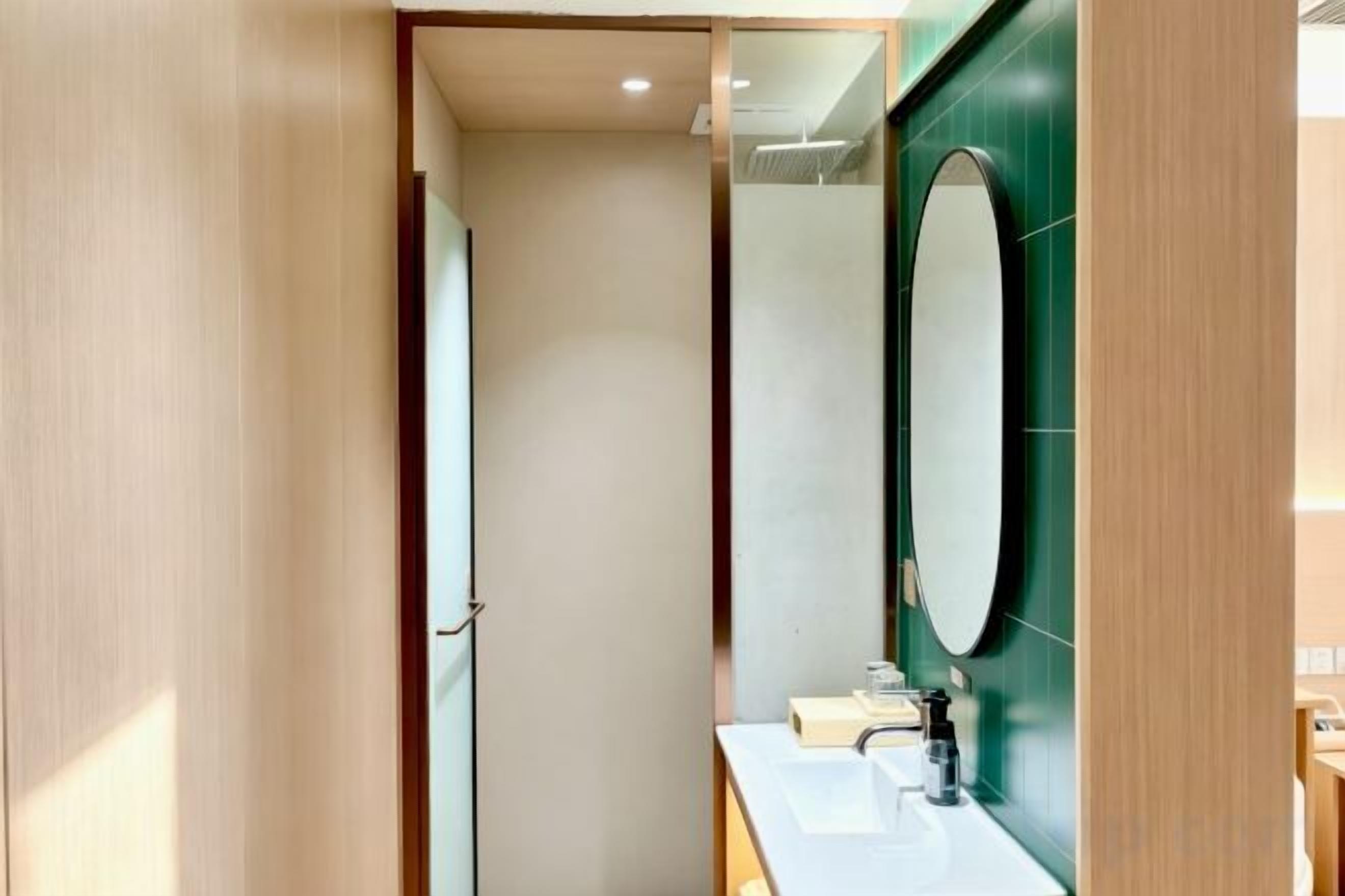 A bathroom with a wooden door, a mirror, and a sink.