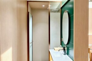 Un baño con puerta de madera, un espejo y un lavamanos.