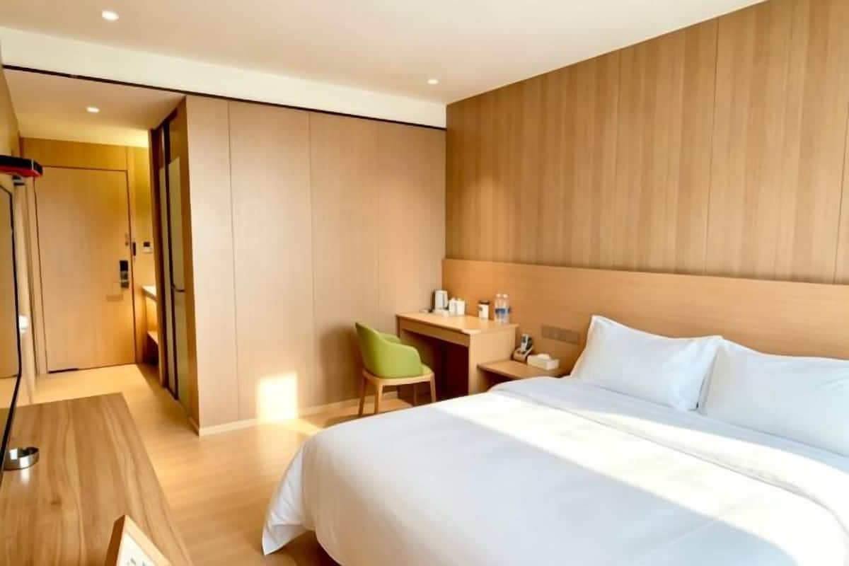 Hotellihuone, jossa on sänky, työpöytä, tuoli ja vaatekaappi.