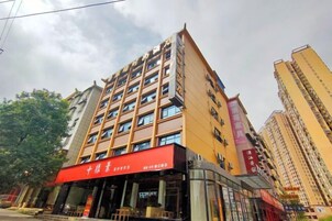Un hotel de varios pisos con un toldo rojo y señalización que indica que es un hotel.