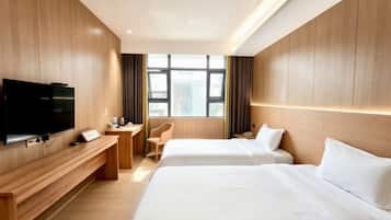 A hotel room with two beds, a desk, a chair, a TV, and a window with curtains.