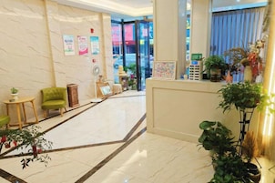 Un vestíbulo de hotel con mostrador de recepción, zona de estar y plantas en macetas.