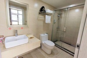 Een badkamer met een wit wastafelmeubel, een toilet en een douche met glazen wand.