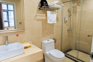 Een badkamer met een wit wastafelmeubel, toilet en douche met glazen wanden.