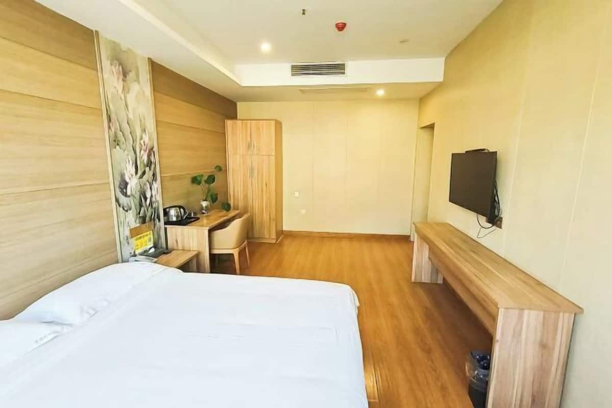 Hotellihuone, jossa on sänky, työpöytä, tuoli, televisio ja vaatekaappi.