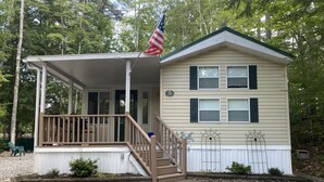 A two-story house with a porch, a flag, and a number '29' sign. - Point Sebago 3 BR, 1.5 bath Maine lake cottage near beach on Purple Rd (Casco)