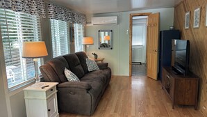 A compact living space with a sofa, two lamps, a television on a wooden cabinet, and a small cabinet with keys. - Point Sebago 3 BR, 1.5 bath Maine lake cottage near beach on Purple Rd (Casco)