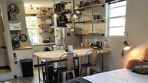 Een compacte, goed verlichte kamer met kitchenette, eethoek en een bed.