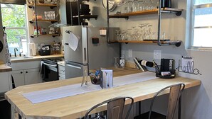 Een moderne keuken met een centraal kookeiland, barstoelen en diverse apparaten.