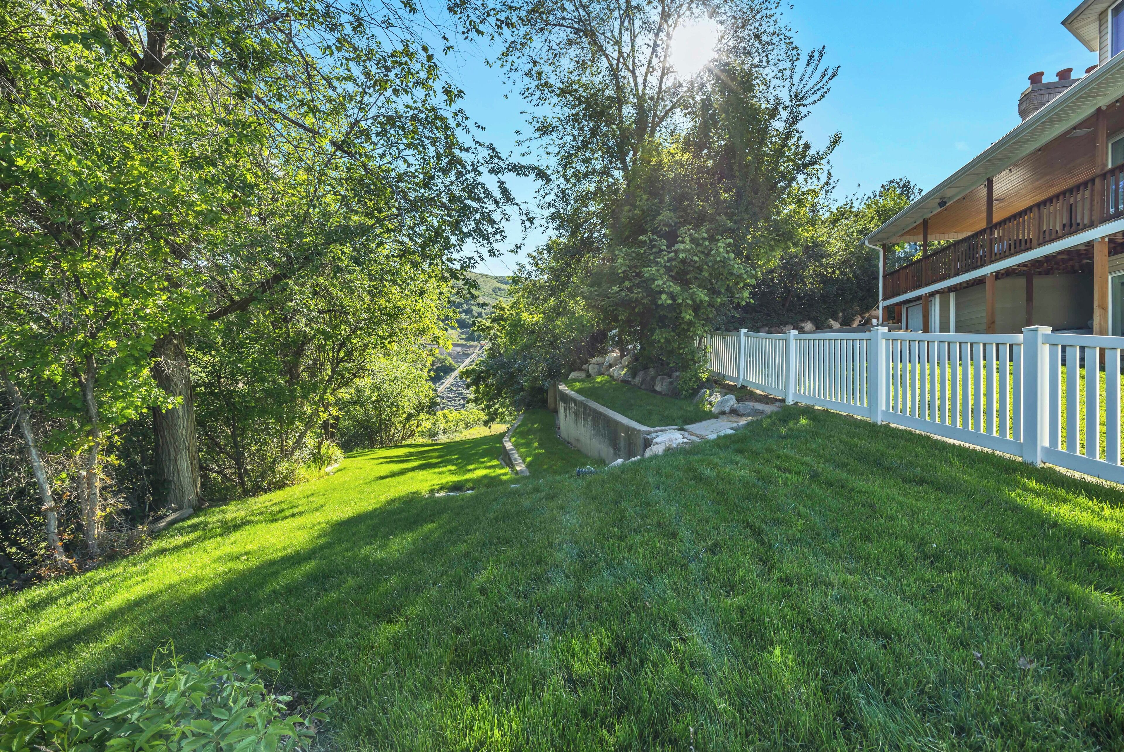 A well-maintained lawn, a white fence, and a building with a balcony.