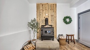 A cozy room with a wood-burning stove, a potted plant, a wicker basket, and a small stool. - Mountain View Retreat: 2 BR/2 BA Spacious & Cozy! (Bountiful)