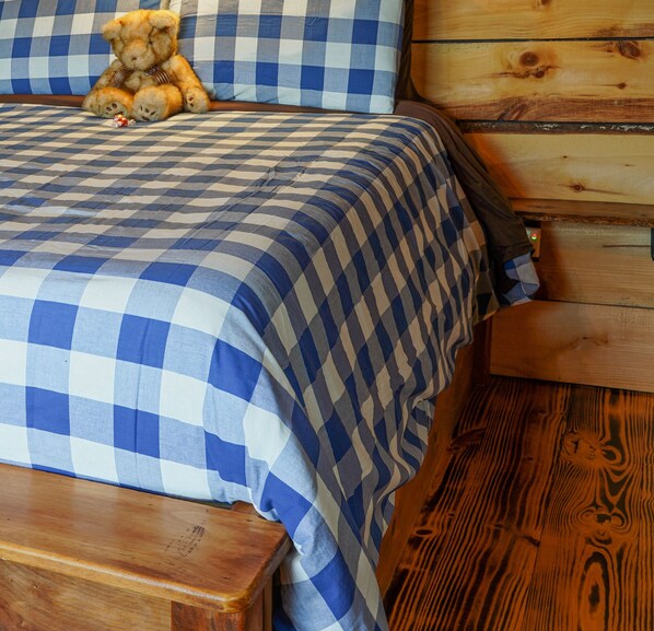 A bed with a blue and white checkered bedspread, a wooden headboard, and a wooden floor. - 2 Log Cabins Retreat in the Smoky Mountains (Cosby)