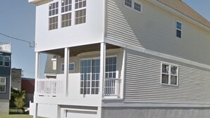 Une maison à deux étages avec un porche à l’avant et un garage.