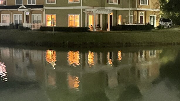 Ein mehrgeschossiges Gebäude mit einer symmetrischen Fassade, großen Fenstern und einem Spiegelbild im darunterliegenden Wasser.