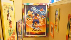 Ein Korridor mit gerahmten Postern an den Wänden, darunter Mickey Mouse und Aladdin.