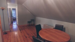 Een zolderkamer met een houten vloer, een ronde tafel en twee stoelen.