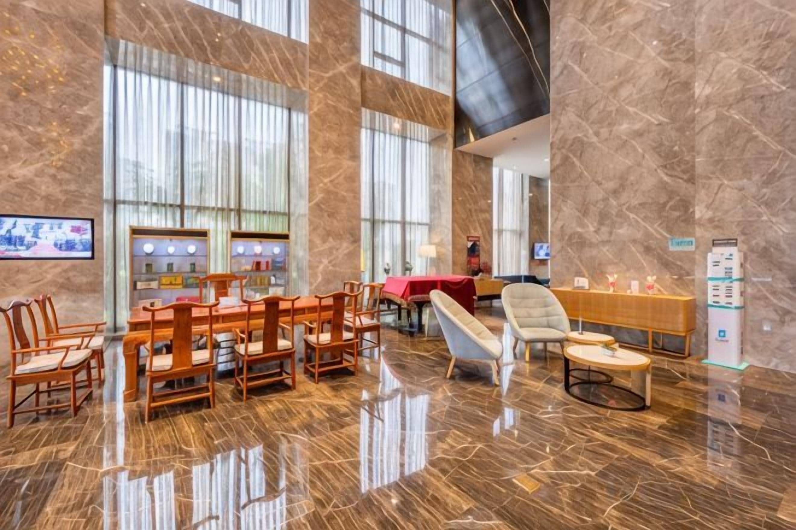 A spacious lobby with a reception desk, seating area, and a television screen.
