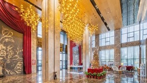Un vestíbulo amplio con techos altos, ventanas grandes y candelabros modernos.