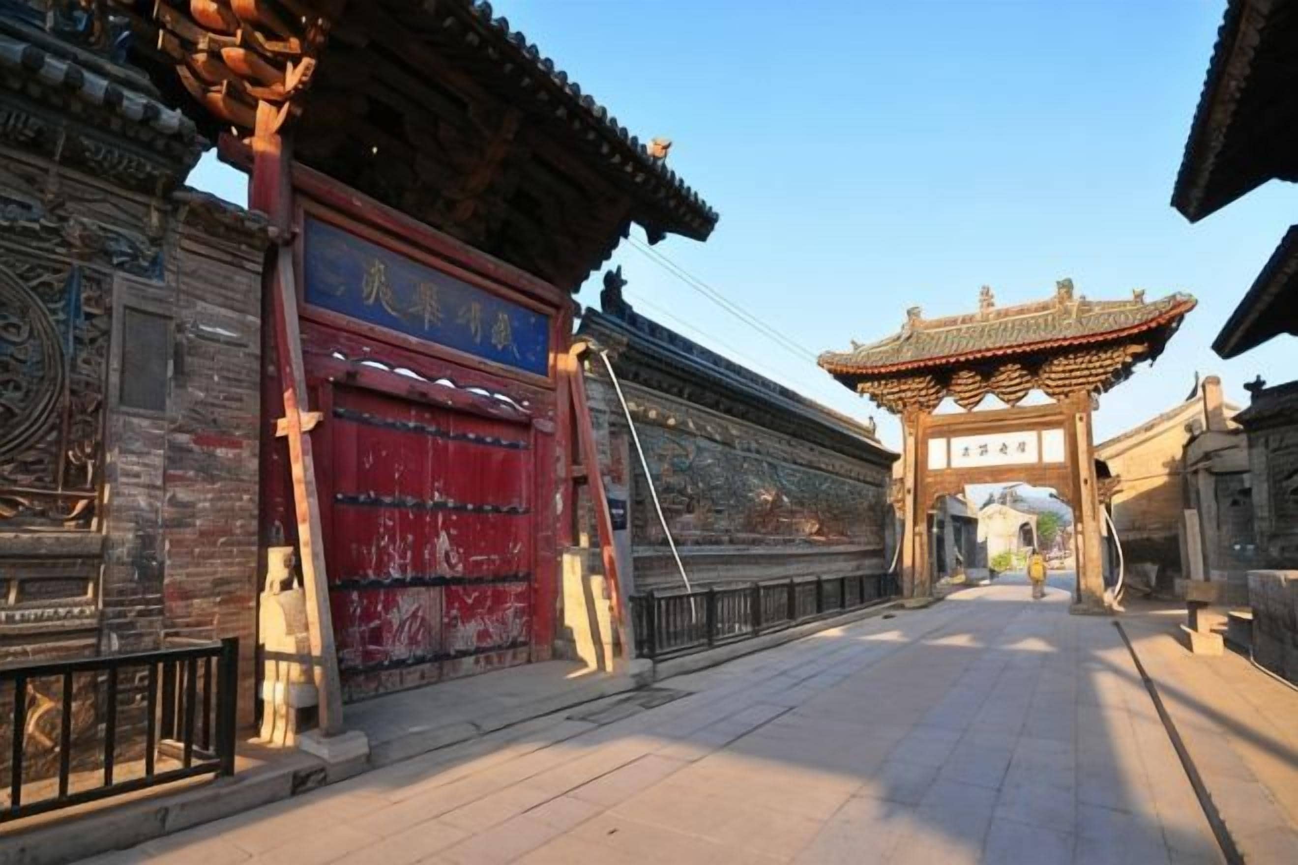 A traditional Chinese gate with intricate carvings and a red door.