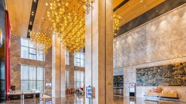 Un hall espacioso con suelos de mármol, ventanas amplias y lámparas colgantes.