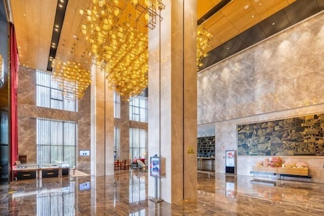 A spacious lobby with marble floors, large windows, and hanging light fixtures.. Grand Skylight Hotel