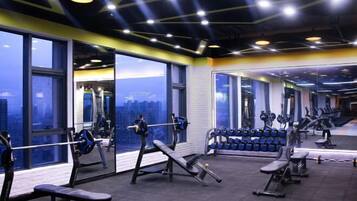 A gym with weightlifting equipment, benches, and dumbbells.