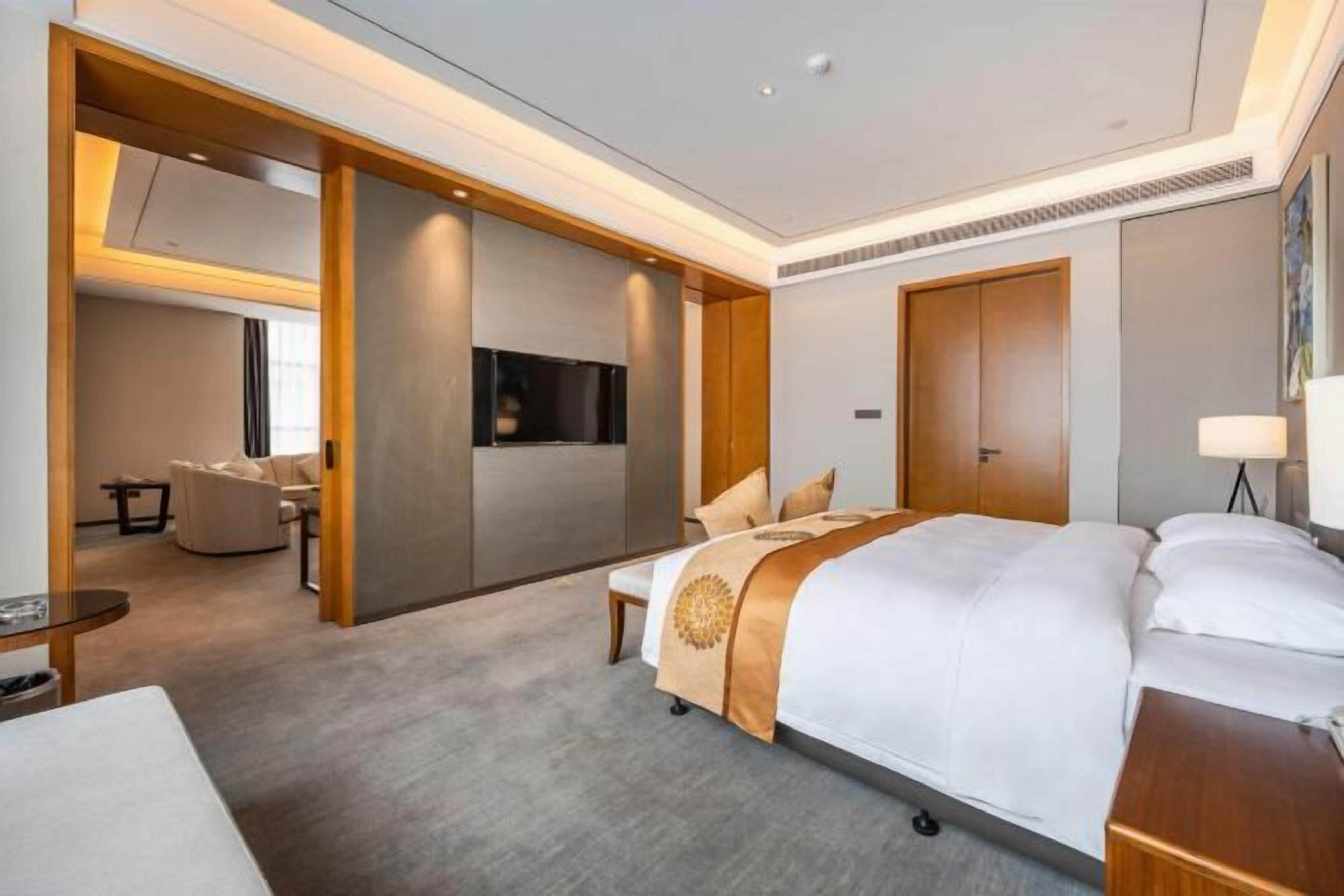 A hotel room with a large bed, a desk, a chair, and a TV.