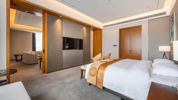 A hotel room with a large bed, a desk, a chair, and a TV.