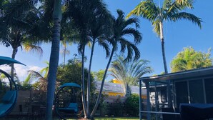 Un jardin avec une balançoire, un espace détente abrité et un barbecue.