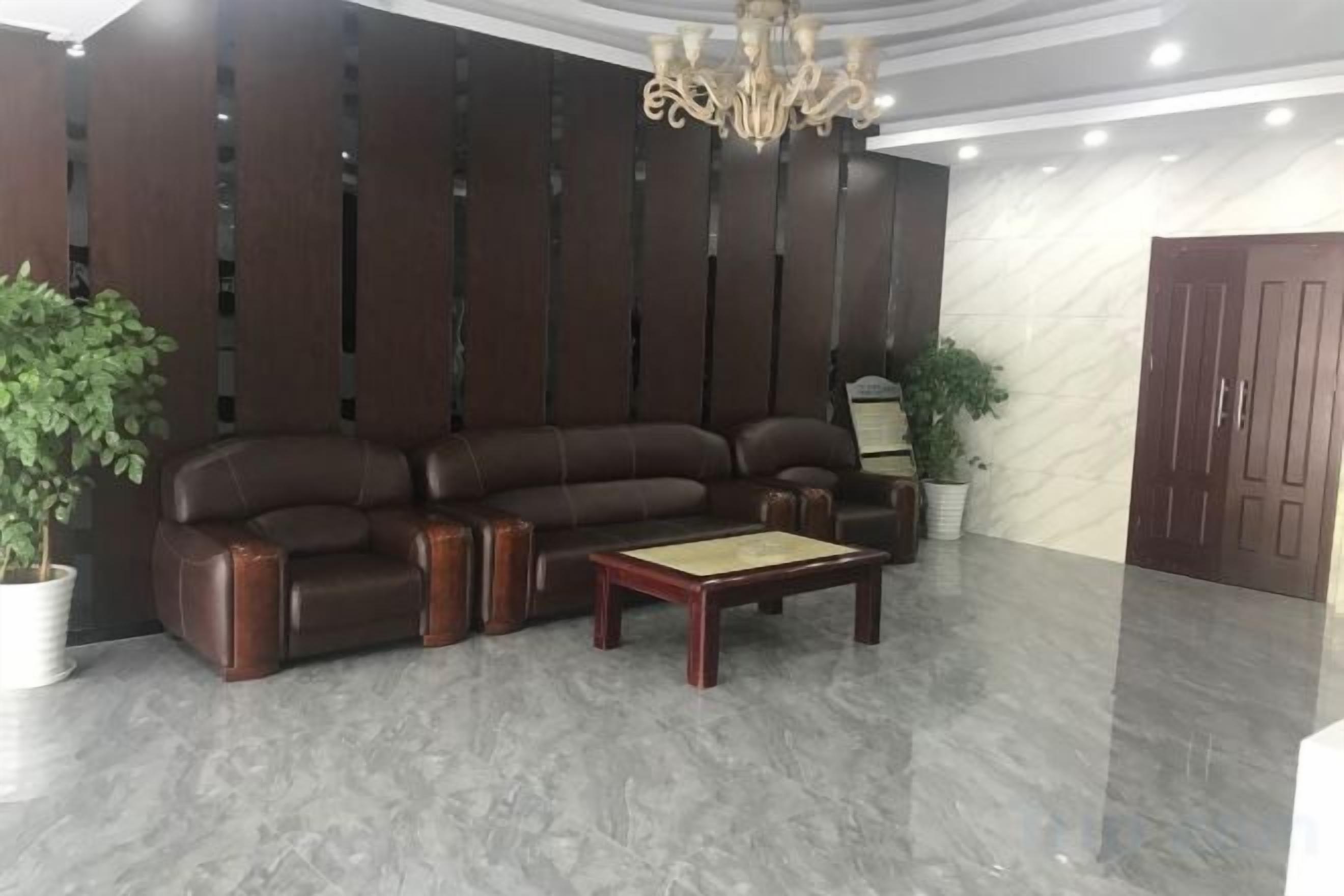 A lobby with a dark-colored sofa, a wooden coffee table, and a potted plant.