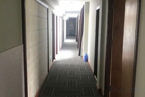 A hallway with a carpeted floor, doors on both sides, and a blue object on the right. - Fuxin Hotel (Xuancheng)