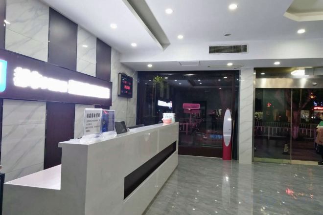 A reception desk with a digital screen, a glass door entrance, and a modern interior design.