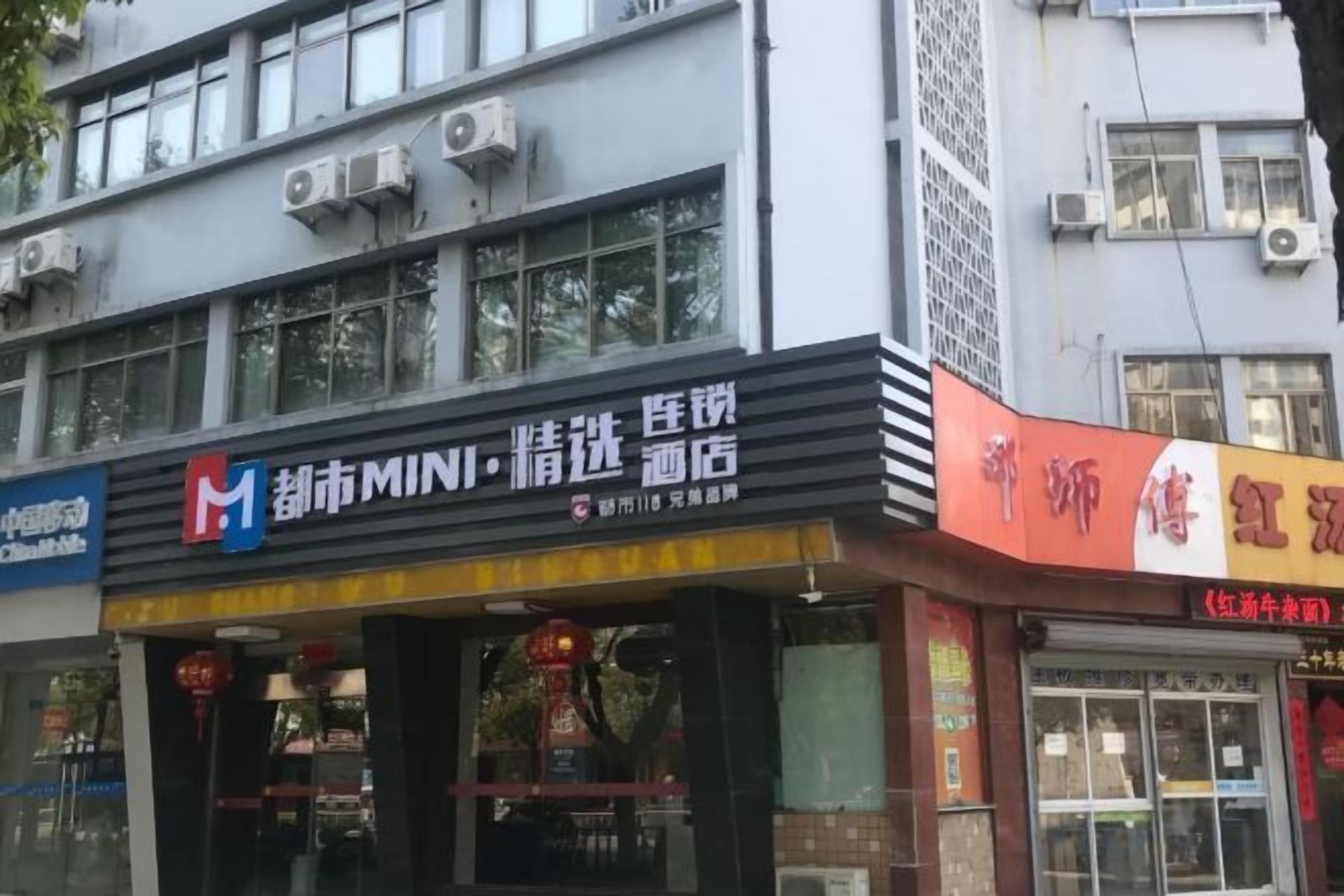 Un immeuble doté de plusieurs devantures de magasins, dont l’une affiche une enseigne avec le mot « MINI » et une autre est ornée de caractères chinois.