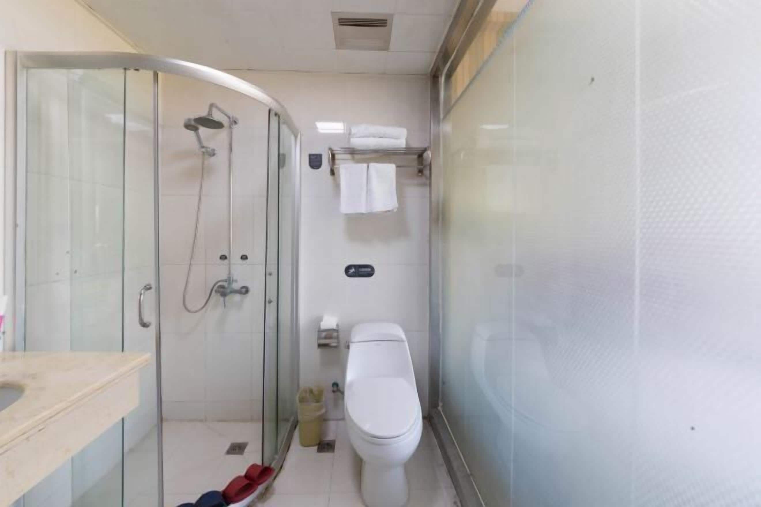 A compact bathroom with a glass-enclosed shower, a toilet, and a sink.