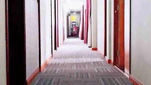 Un pasillo largo y estrecho con puertas a ambos lados y piso alfombrado.