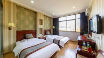 Habitación de hotel con dos camas, un escritorio con silla, televisión y ventana con vistas.