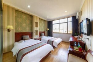 Habitación de hotel con dos camas, un escritorio con silla, televisión y ventana con vistas.