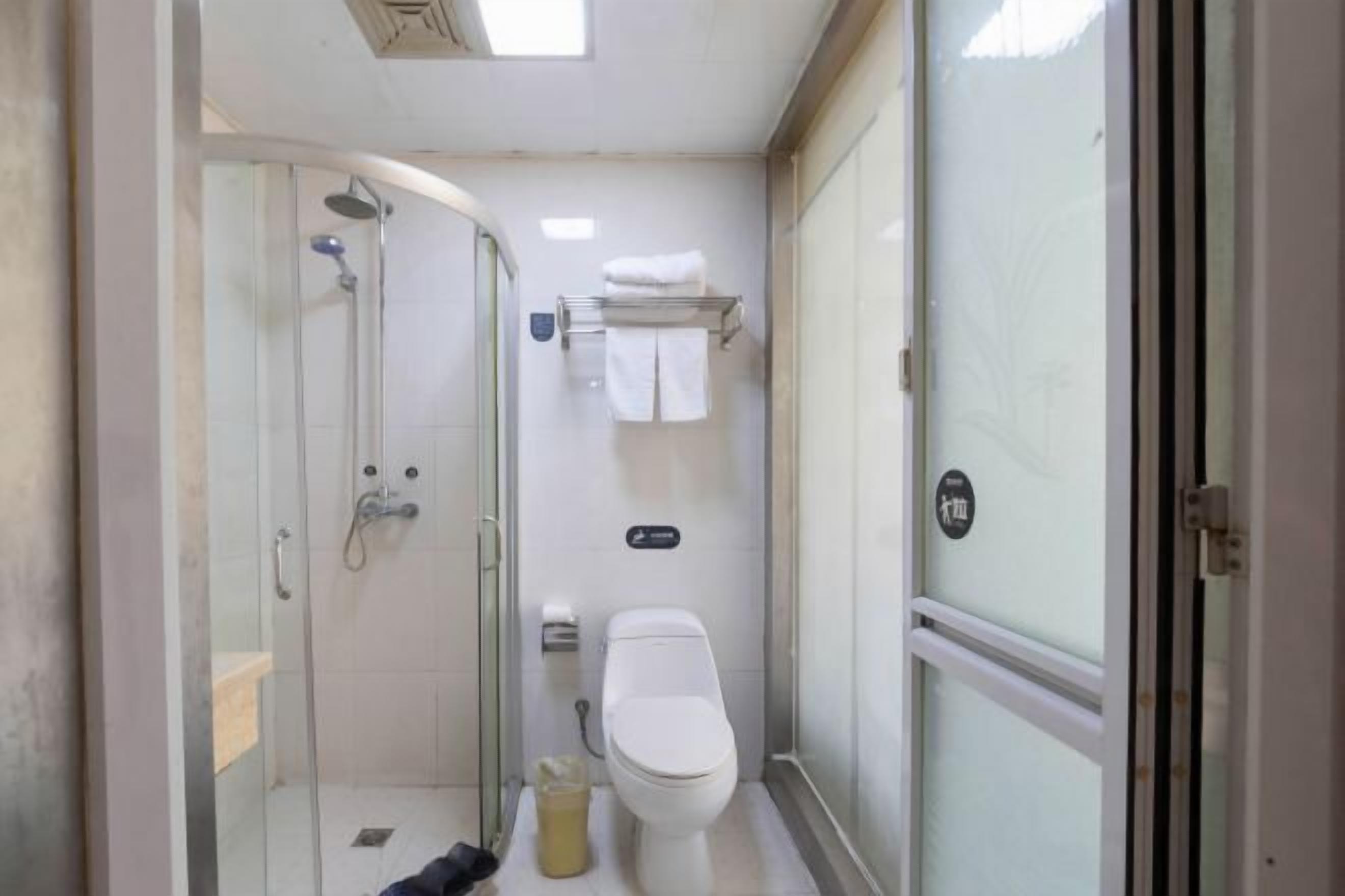 A compact bathroom with a glass shower enclosure, a toilet, and a towel rack.