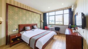 Una habitación de hotel con una cama grande, un escritorio, una silla, un televisor y una ventana con vista a la ciudad.