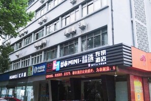 A building with multiple storefronts, including one with a sign for 'HUAWEI' and another for 'MINI'. - Fuxin Hotel (Xuancheng)