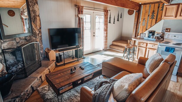 Una sala de estar acogedora con chimenea, televisor y zona de cocina con estufa.
