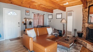 Una sala de estar acogedora con un sofá de cuero, una mesa de centro de madera y una chimenea de piedra.