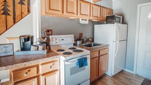 Una cocina con armarios de madera, estufa, microondas y refrigerador.